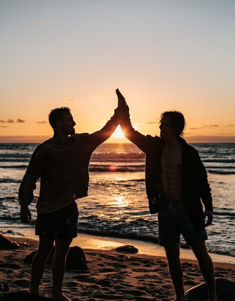 two men clapping each other on shore